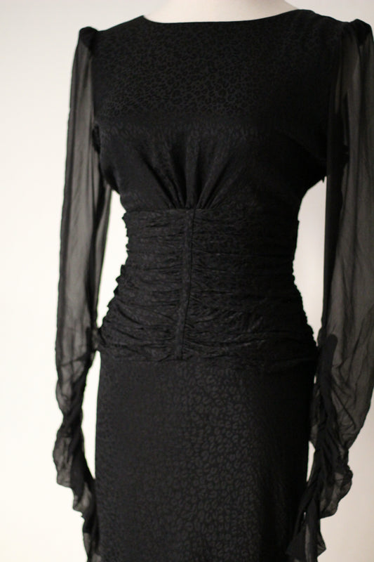 Front view of Emanuel Ungaro FW 2006 black dress with a rounded neckline, sheer long sleeves, and a ruched waist.