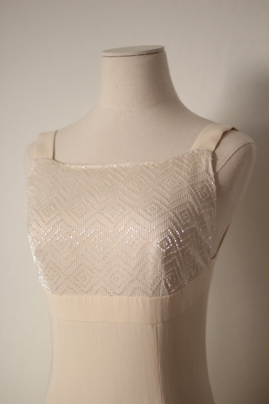 Close-up front view of the Giorgio Armani Le Collezioni 1990s cream-white bridal dress featuring a square neckline, wide shoulder straps, and intricate geometric beading across the bodice.
