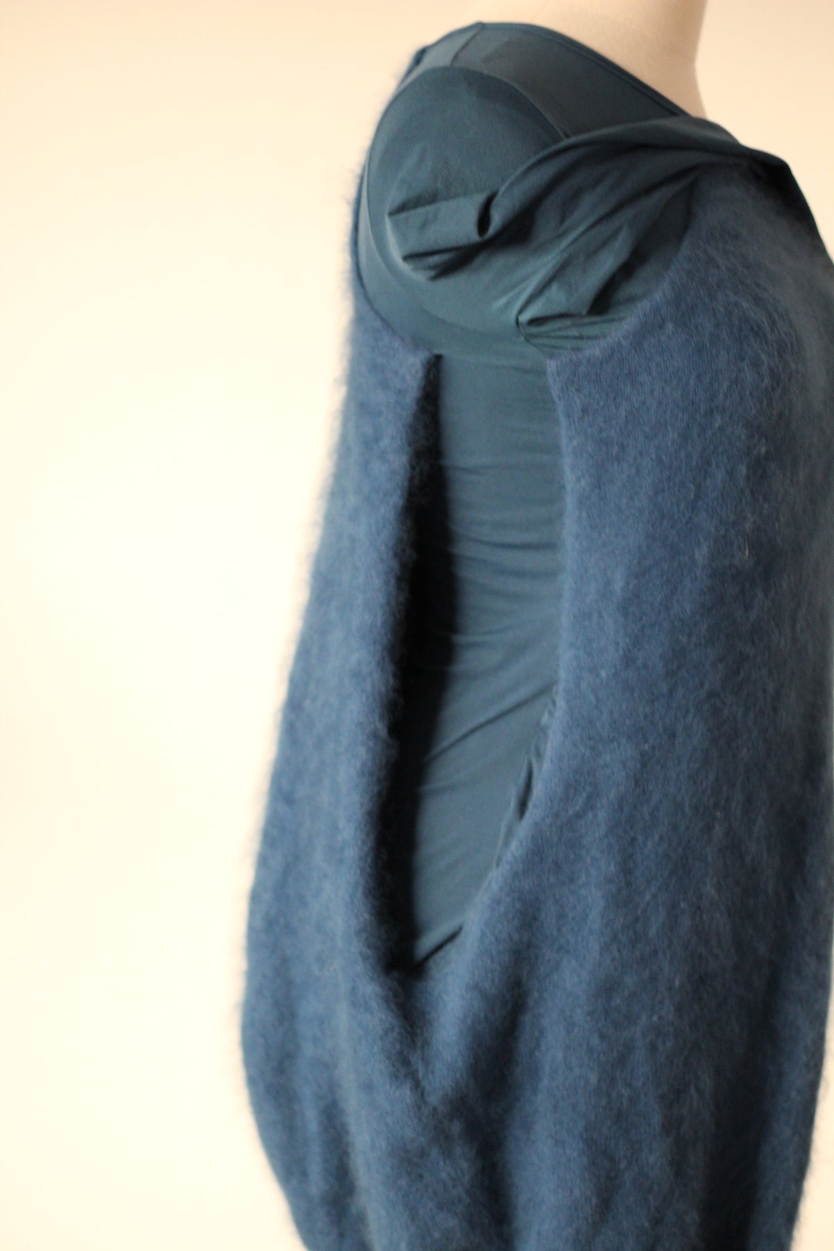 Close-up side view of Alexander McQueen Fall/Winter 2007 blue angora sweater dress showing the open side of the textured outer layer, fitted blue inner dress, and gathered sleeve fabric.