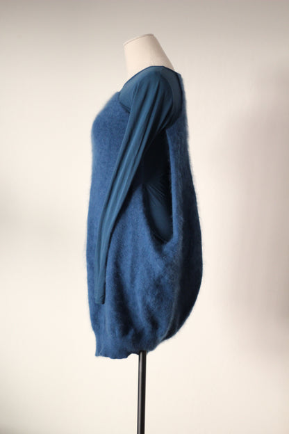 Side view of Alexander McQueen Fall/Winter 2007 blue angora sweater dress featuring a fuzzy textured exterior, long sleeves, an open side revealing the fitted inner dress, and a rounded cocoon silhouette.