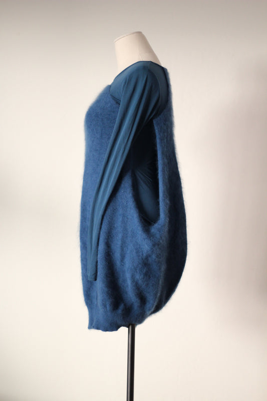 Side view of Alexander McQueen Fall/Winter 2007 blue angora sweater dress featuring a fuzzy textured exterior, long sleeves, an open side revealing the fitted inner dress, and a rounded cocoon silhouette.