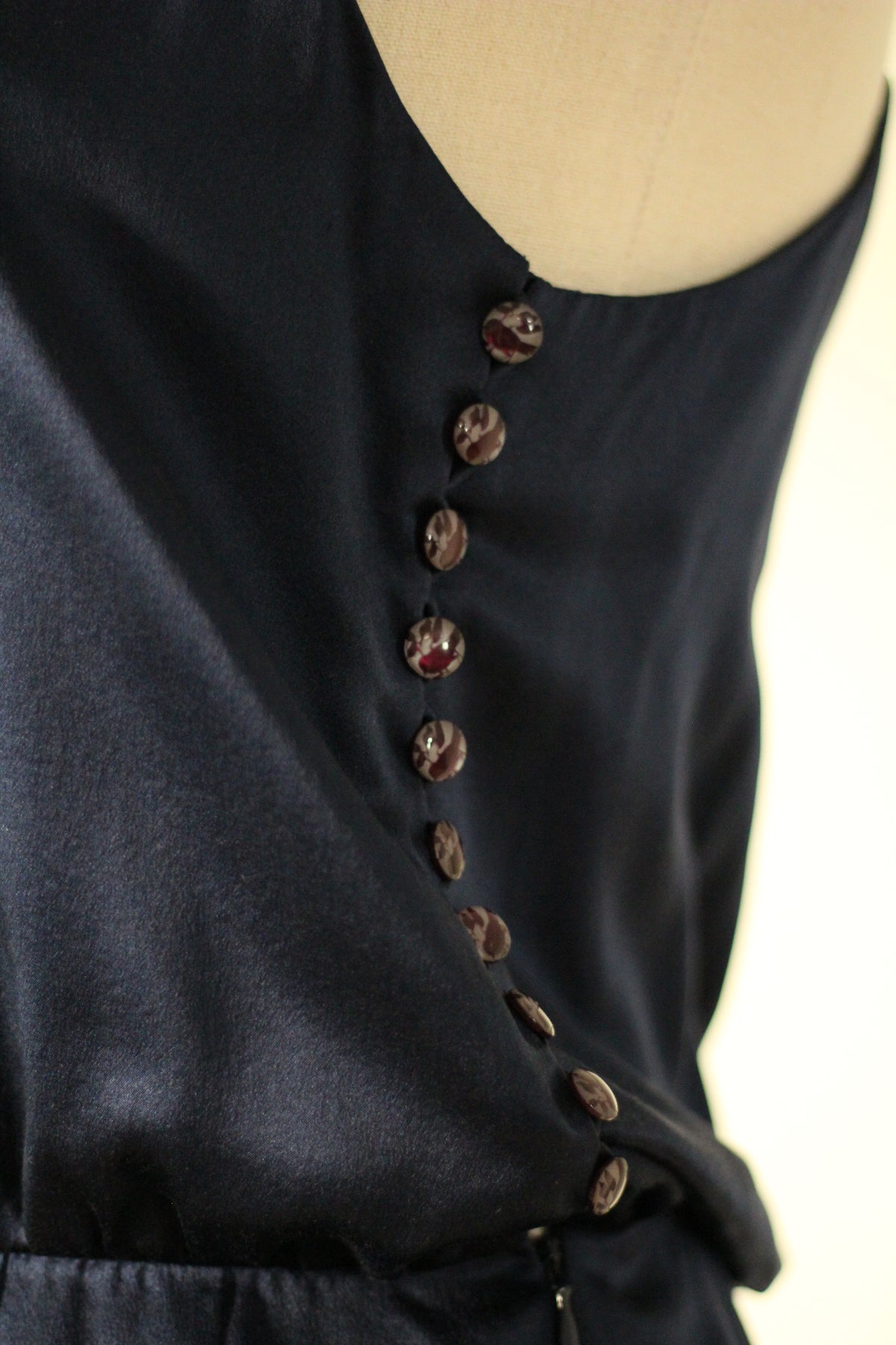 Close-up of the Chloé Spring/Summer 1999 navy blue silk runway dress featuring a row of decorative buttons along the side of the bodice. 