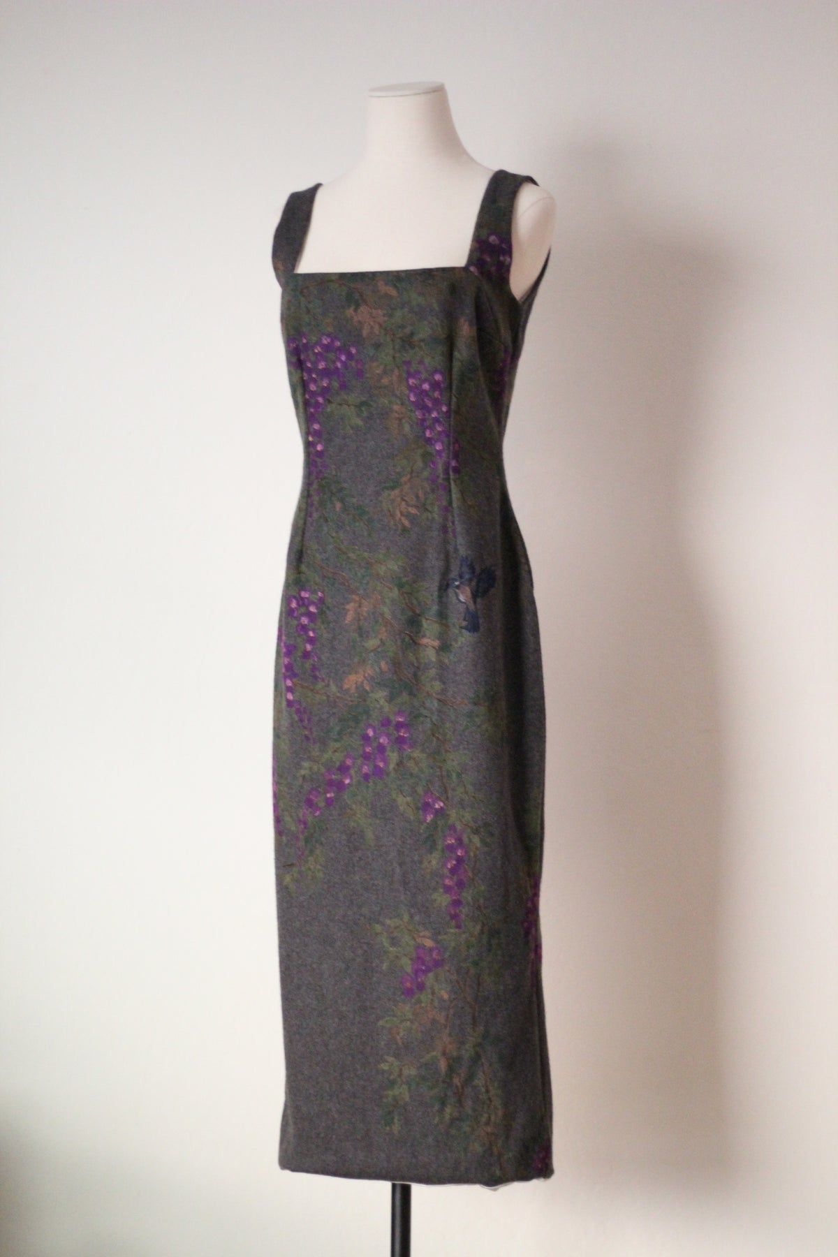 Angled front view of vintage Dolce & Gabbana Fall/Winter 1998 runway dress featuring a square neckline, fitted silhouette, and purple wisteria flowers with painted bird details on gray wool fabric.