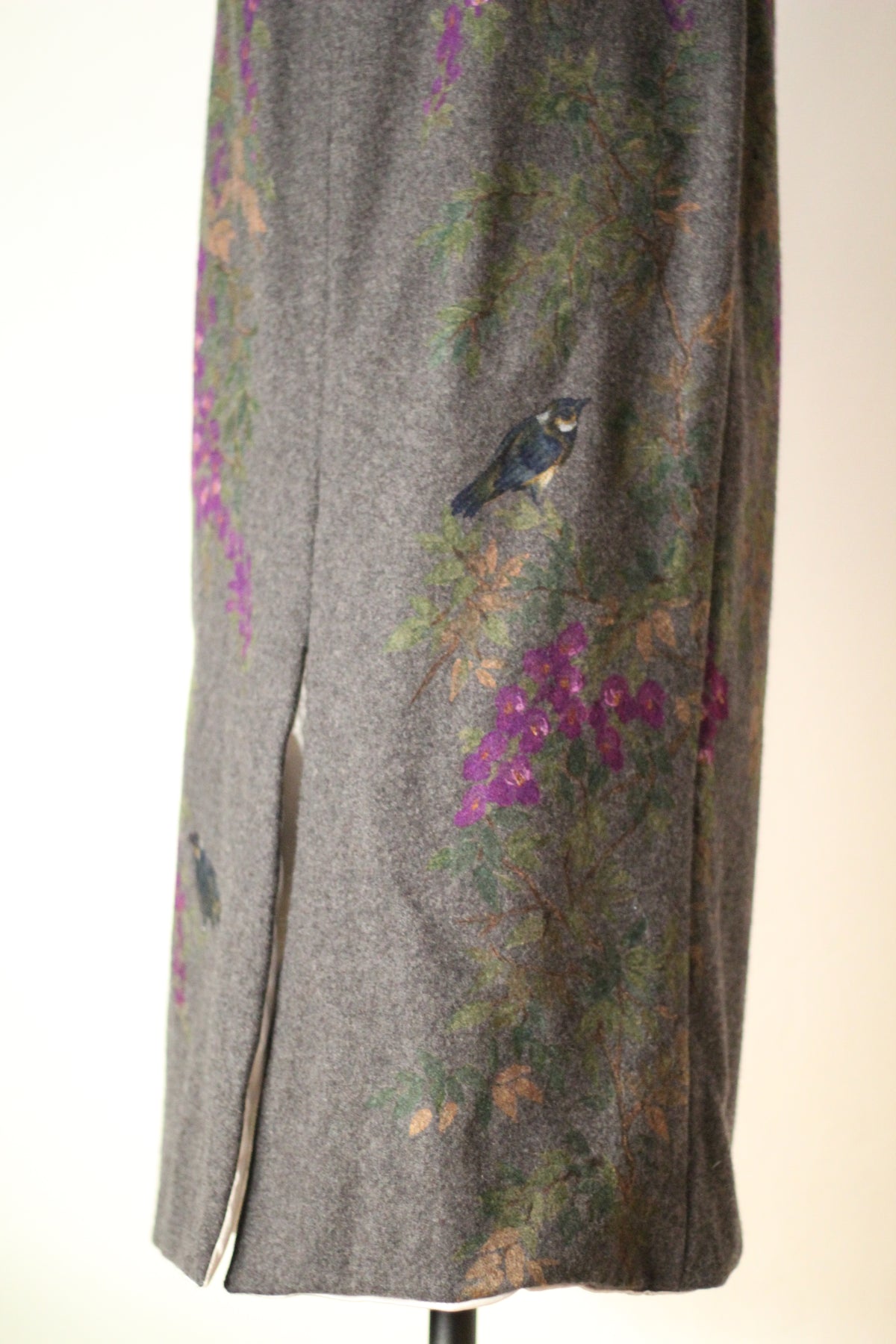 Back detail of vintage Dolce & Gabbana Fall/Winter 1998 runway dress featuring a back slit, painted blue bird, purple wisteria flowers, and green foliage on gray wool fabric.