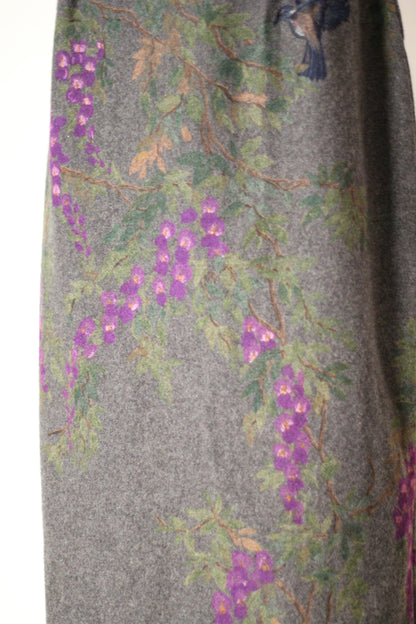 Close-up of vintage Dolce & Gabbana Fall/Winter 1998 runway dress featuring hand-painted purple wisteria flowers, green leaves, delicate branches, and a partial blue bird motif on gray wool fabric.