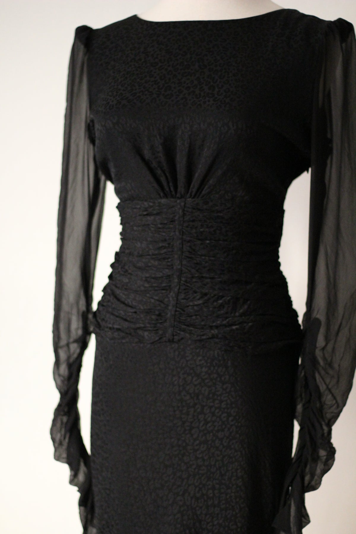 Front view of Emanuel Ungaro FW 2006 black dress with a rounded neckline, sheer long sleeves, and a ruched waist.