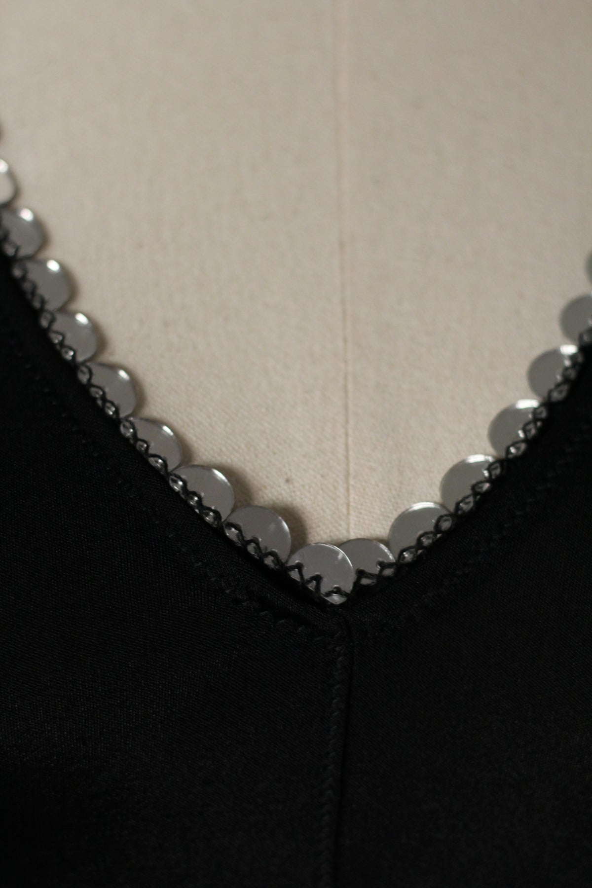 Close-up of the vintage Prada Spring/Summer 1999 black top featuring small circular mirror embellishments and decorative stitching along the V-neckline.