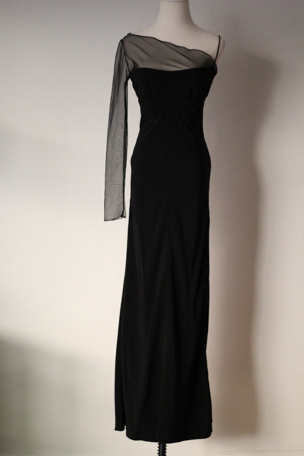 Black Richard Tyler Spring/Summer 1997 floor-length gown with an asymmetrical neckline, sheer mesh overlay, and long sleeve