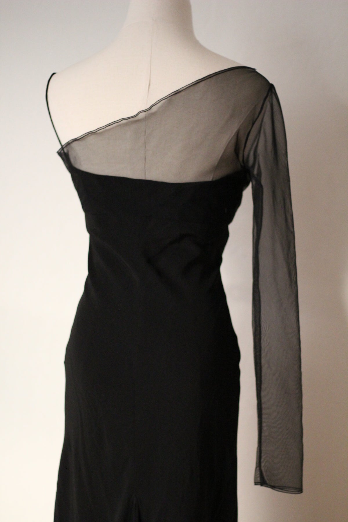 Close-up of a black Richard Tyler gown featuring a sheer mesh neckline, asymmetrical shoulder, and fitted black bodice