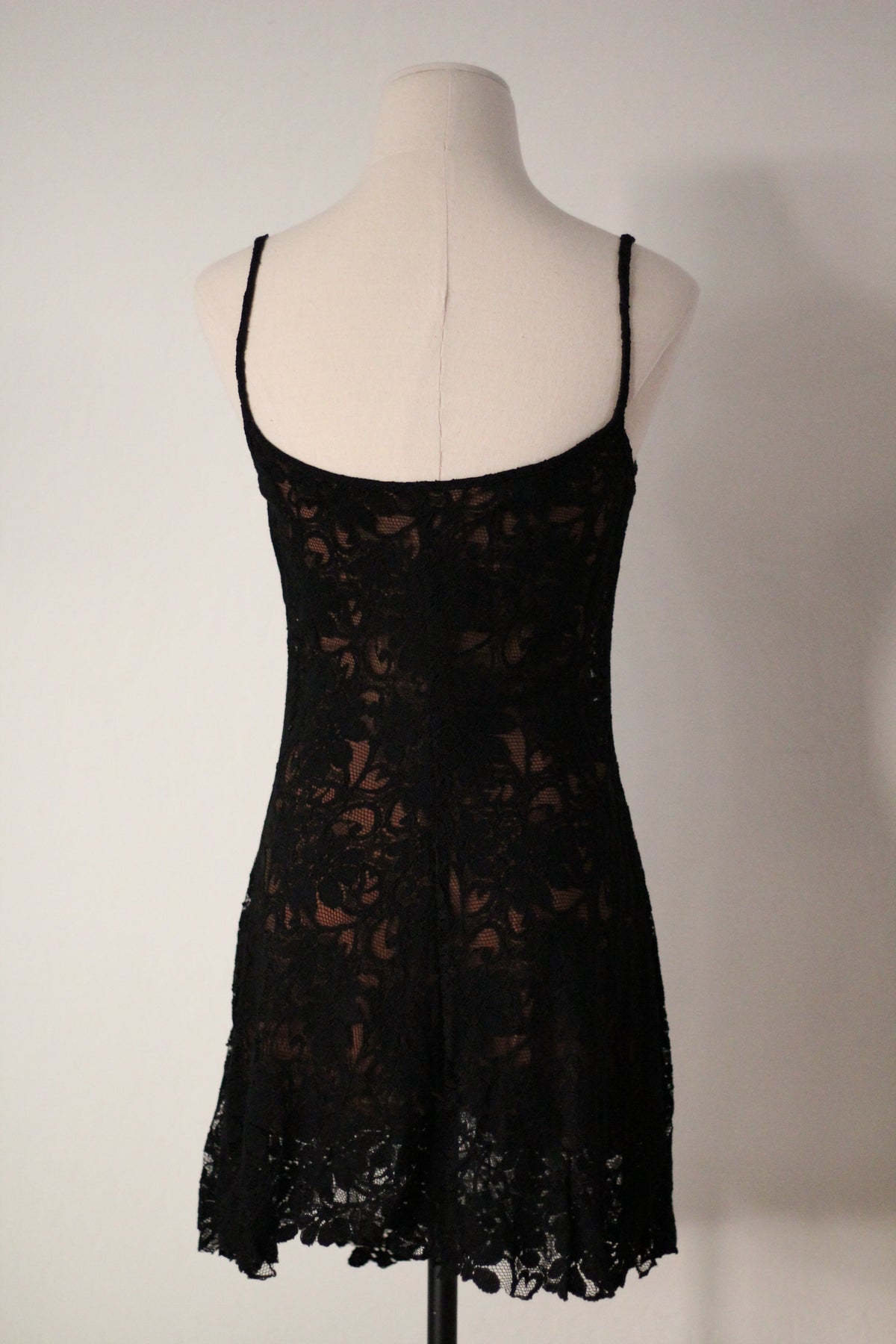 Back view of Rifat Ozbek Spring/Summer 1994 black lace runway mini dress featuring thin spaghetti straps, a low scoop back neckline, floral lace overlay, and a scalloped lace hem.