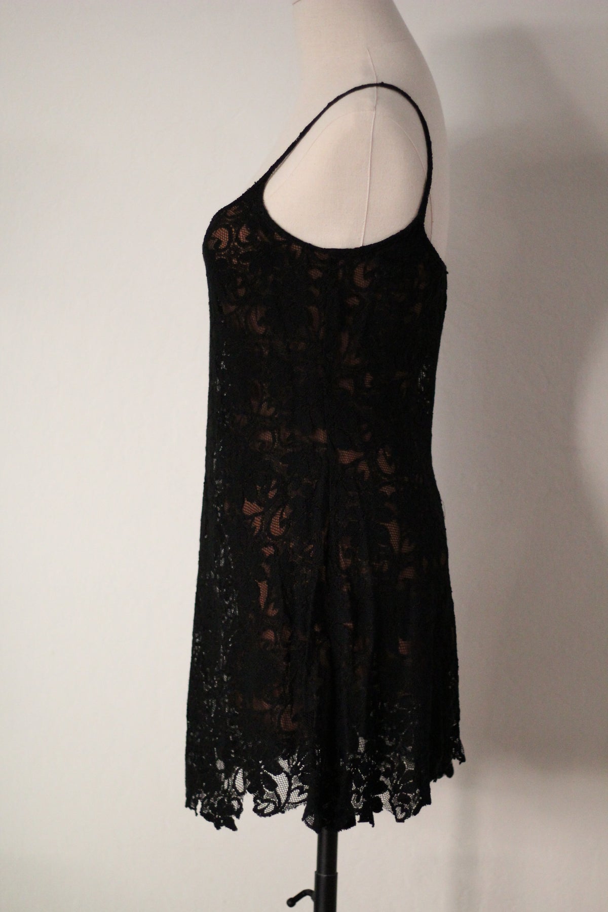 Side view of Rifat Ozbek Spring/Summer 1994 black lace runway mini dress featuring thin spaghetti straps, a floral lace overlay, a fitted bodice, and a scalloped lace hem.