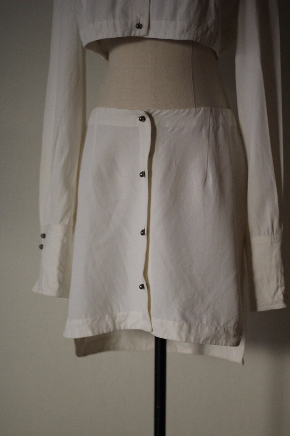 Close-up front view of the Rifat Ozbek Spring/Summer 1994 white mini skirt featuring an asymmetrical button-front design.