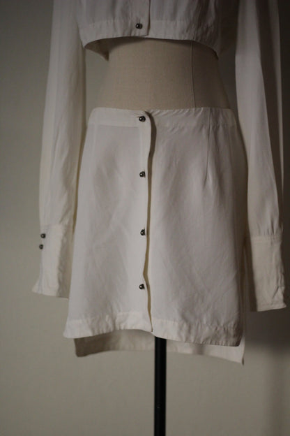 Close-up front view of the Rifat Ozbek Spring/Summer 1994 white mini skirt featuring an asymmetrical button-front design.