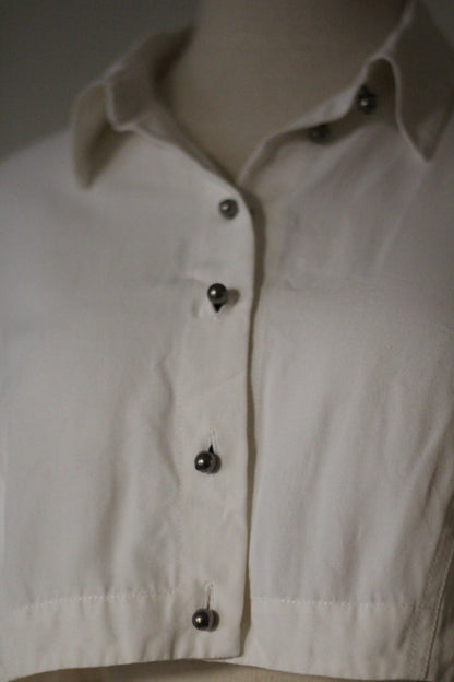 Close-up of the Rifat Ozbek Spring/Summer 1994 white cropped shirt featuring a pointed collar and dark button-front detailing.