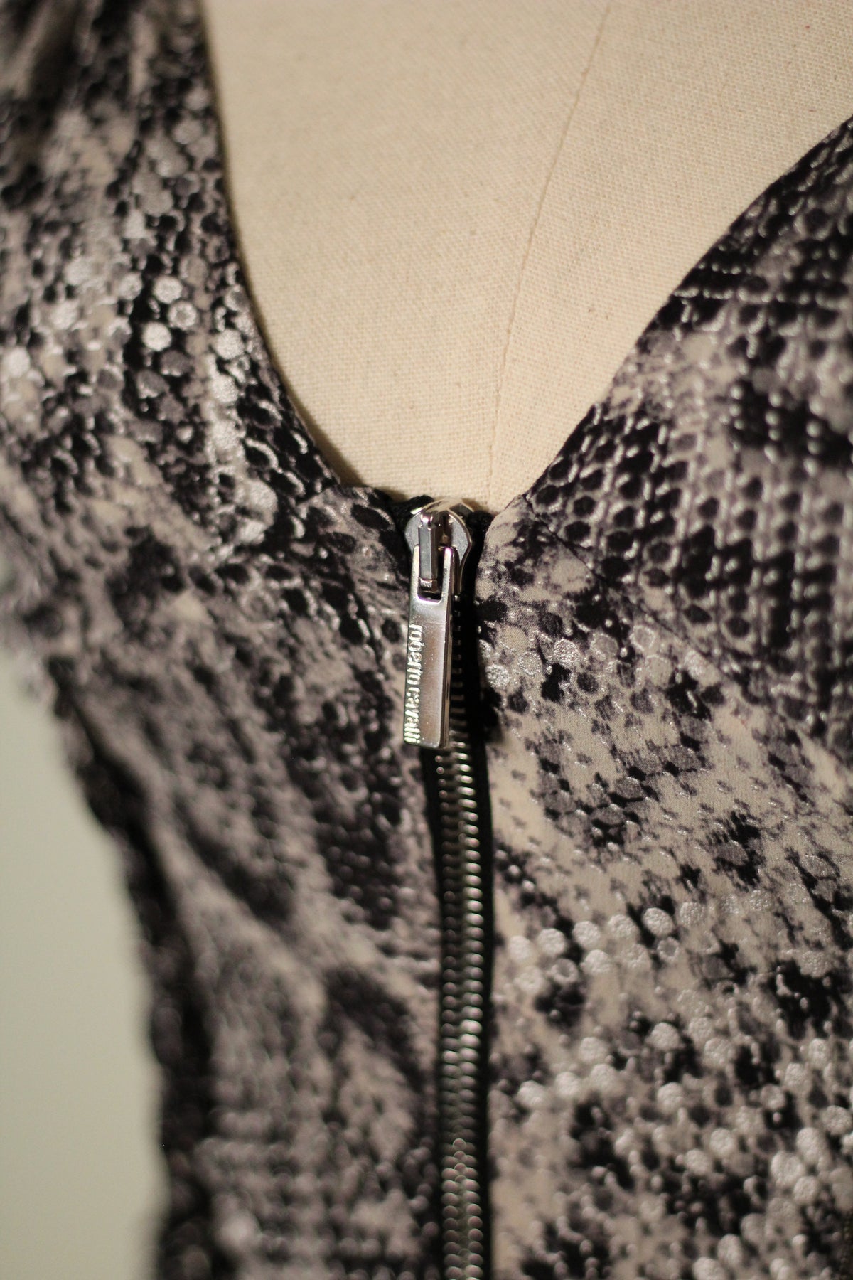 Close-up of the Roberto Cavalli Fall/Winter 2003 reflective snake print top featuring a plunging V-neckline and silver front zipper with engraved Roberto Cavalli branding.