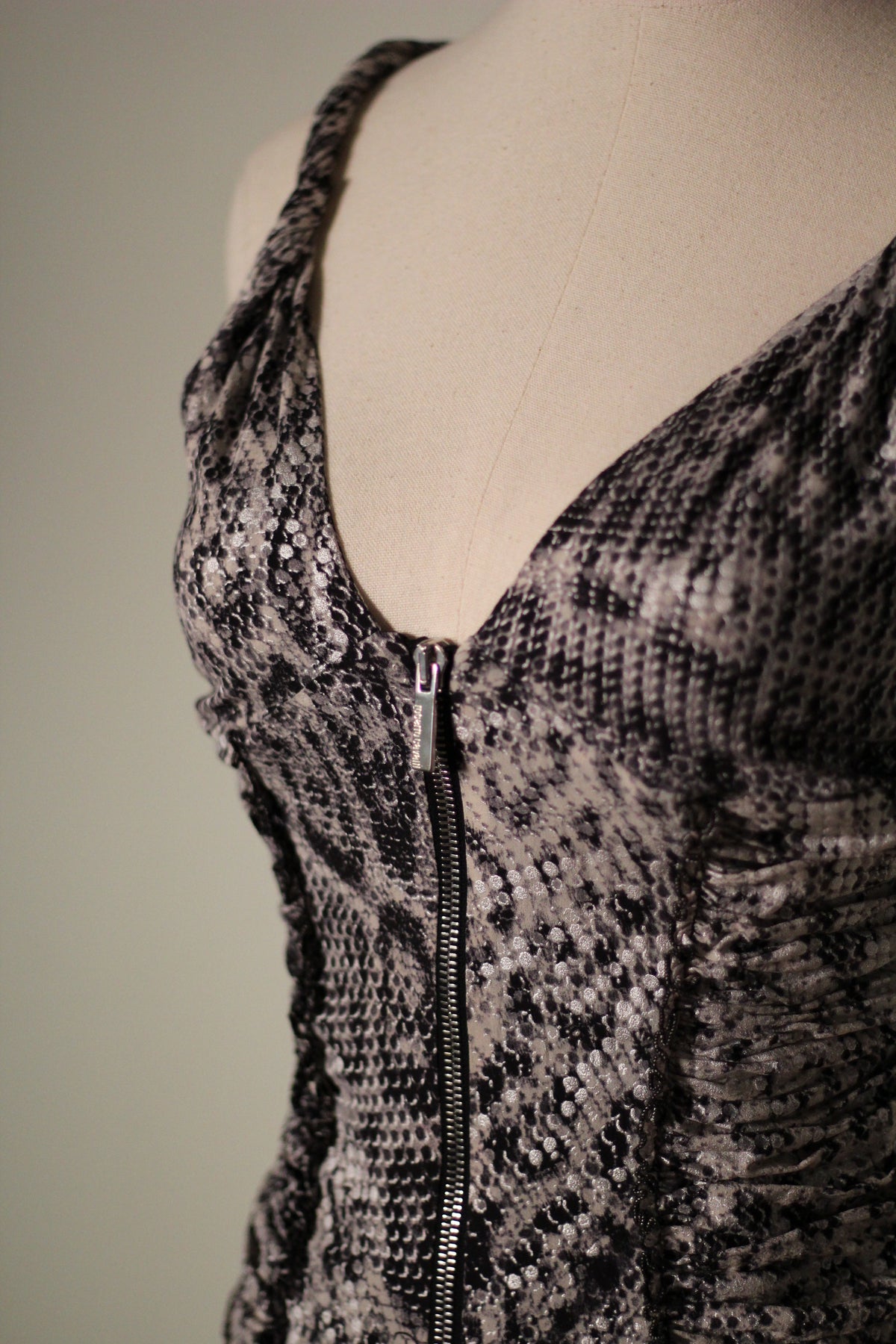 Close-up of the Roberto Cavalli Fall/Winter 2003 reflective snake print top featuring a plunging V-neckline, silver front zipper, and ruched side detailing. 