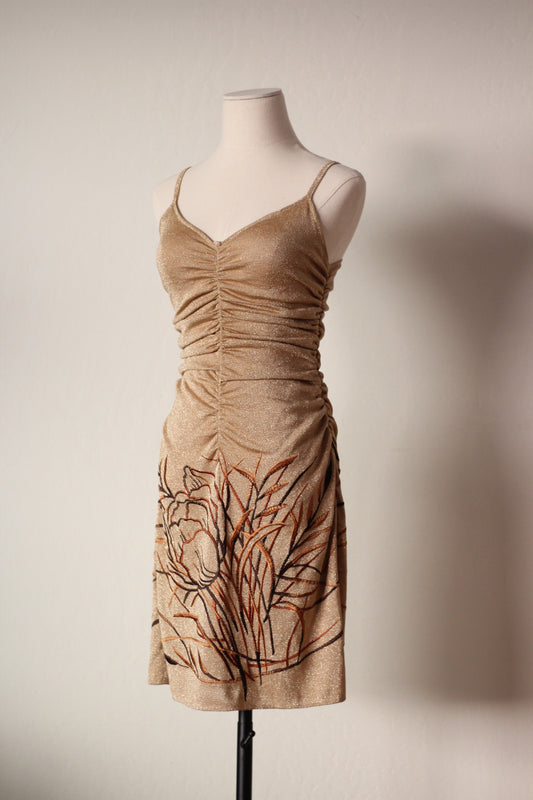 Gold dress with floral embroidery on a mannequin against a plain background